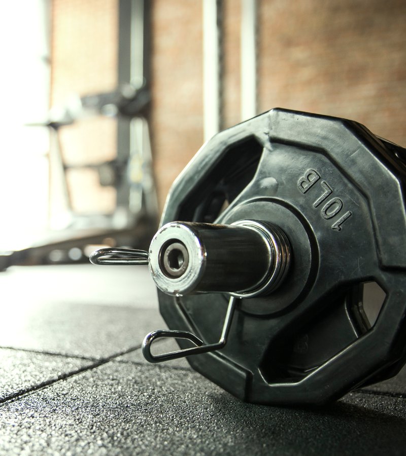 A black hexagonal weight on a weighted bar sits on the gym floor