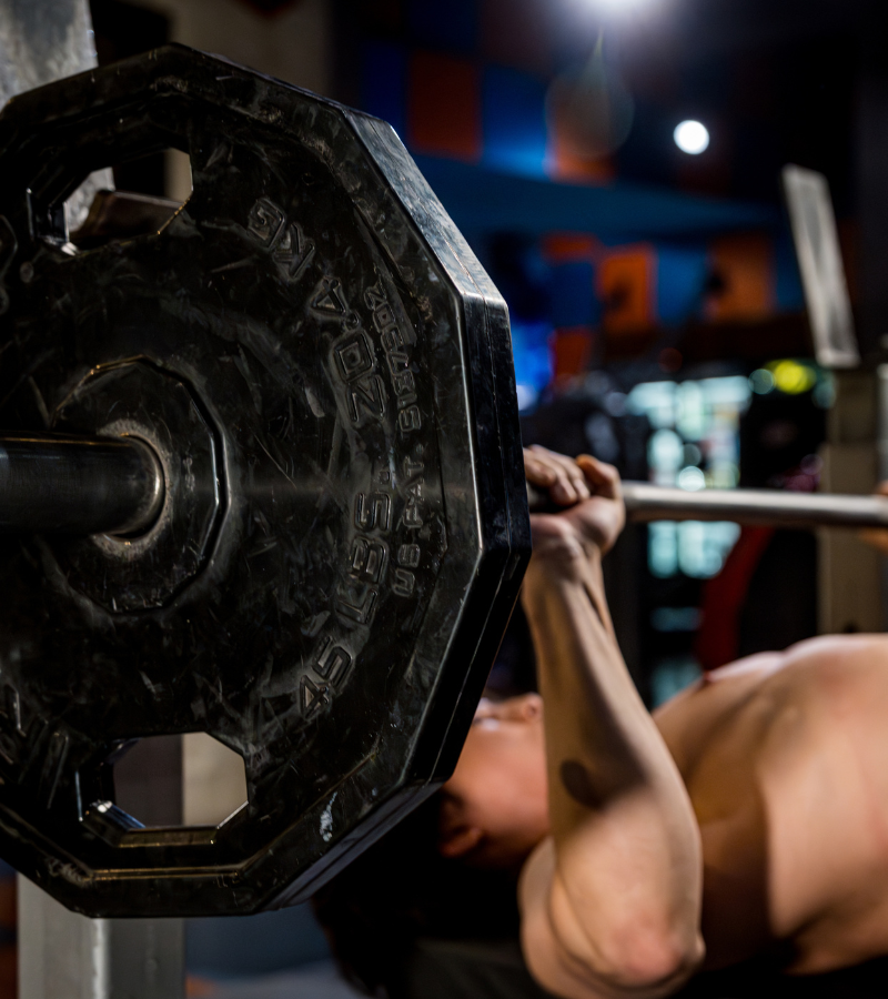 Close-up image of a barbell bench press plate and bar at Mid City Gym & Tanning.