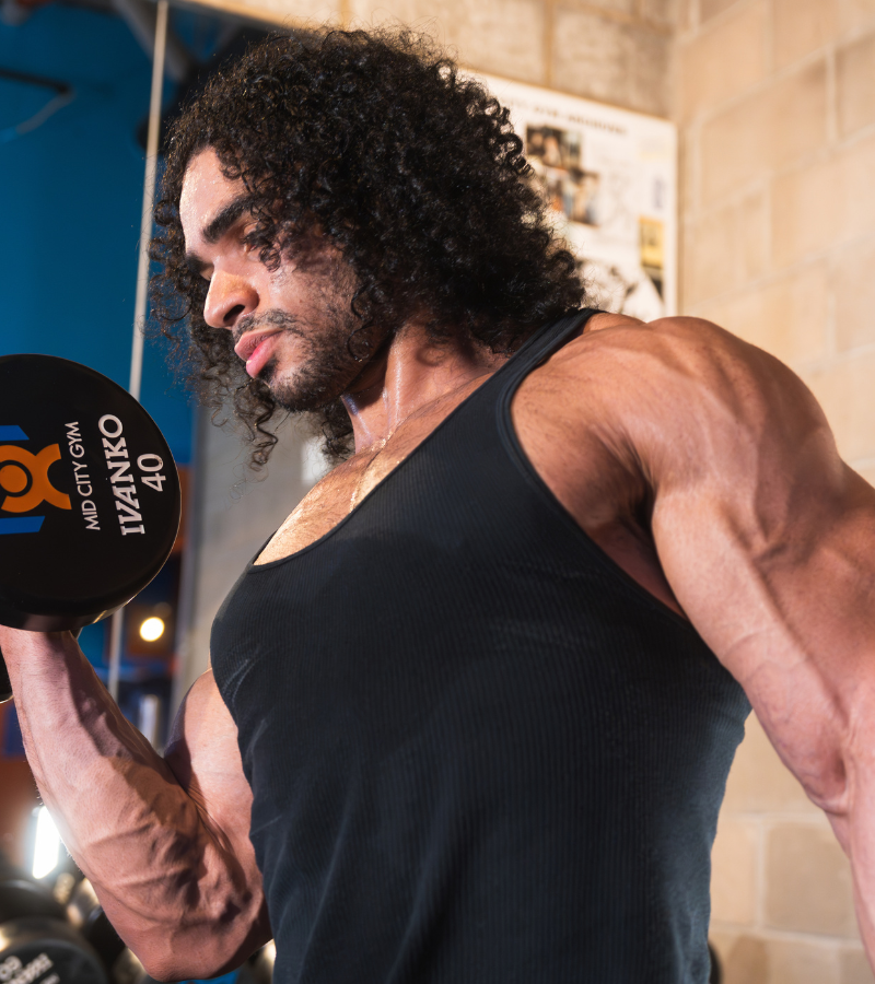 Personal trainer coaching a member on a dumbbell curl at Mid City Gym & Tanning.
